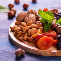 Healthy concept: assortment of dry fruits and nuts on blue rustic background. Selective focus