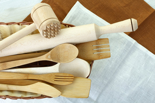 Wooden kitchen utensils in a basket on a kitchen napkin
