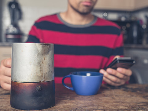 Young man drinking coffee and using smart phone