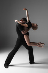 two young modern ballet dancers on gray studio background 