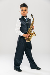 Fototapeta premium six years old boy plays saxophone at studio