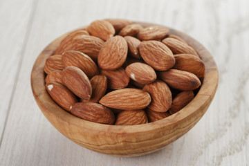 roasted almonds in bowl on white wooden table