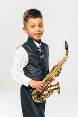 Fototapeta premium six years old boy plays saxophone at studio