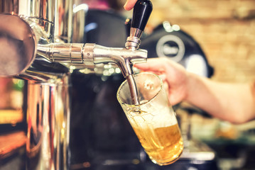 Barmann-Hand am Bierzapfhahn, der ein gezapftes Lagerbier einschenkt, das in einem Restaurant oder einer Kneipe serviert wird
