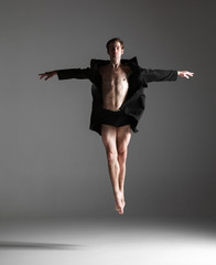 The young attractive modern ballet dancer jumping on white