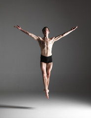 The young attractive modern ballet dancer jumping on white