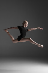 Young beautiful modern style dancer jumping on a studio