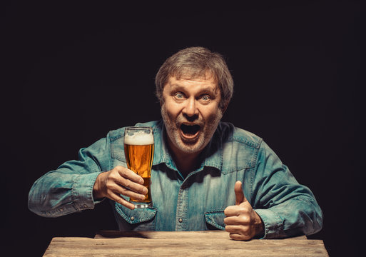The smiling man in denim shirt with glass of beer