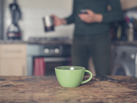 Cup of coffee in kitchen with man in background