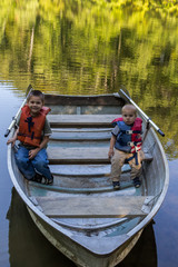 Obraz premium Two young boys sitting in a rowboat on the water.