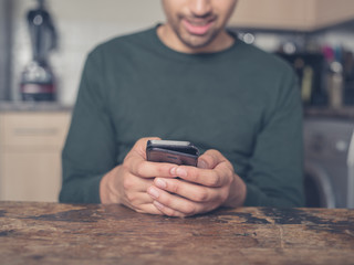 Young man using smart phone in kitchen
