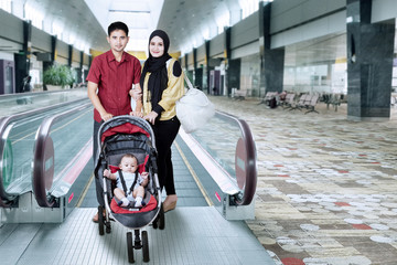 Family in the airport hall with baby on the pram
