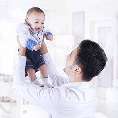 Father lift up male infant in the bedroom