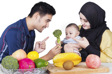 Fototapeta premium Father showing broccoli on his baby