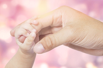 Hand of baby and father with bokeh background