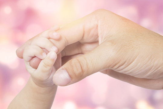 Hand of baby and father with bokeh background