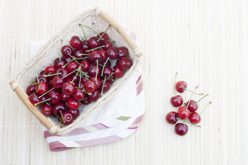 Fresh cherries in wicker basket on lighten makisu