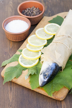 Fresh mackerel on paper in grape leaves with lemon slices