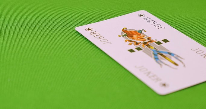 A green table and a person putting a JOKER card on it...