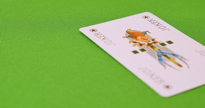 A green table and a person throwing a JOKER card on it
