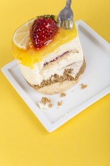 eating delicious cake with lemon and strawberry on yellow background