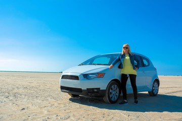 Frau mit ihrem Auto auf dem Sandstrand