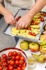 Kitchener puts Potato slices with fresh tomatoes and spices on pan