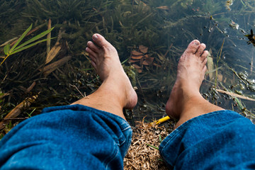 Legs and feet relaxing in front of serene fresh water pond