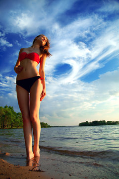 beautiful sexy woman in a swimsuit on the sea coast in summer ev