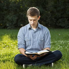 Young man reading Bible in a park