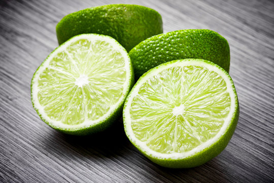 Fresh limes cut in half on wooden surface