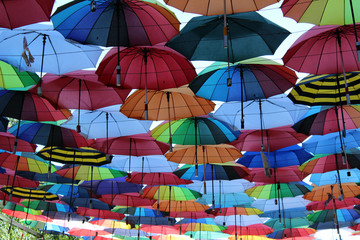 Fototapeta na wymiar Under a rainbow of umbrellas. Soaring in the sky multi-colored umbrellas.