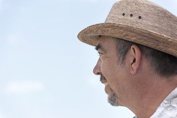 Homme, dans la cinquantaine, en vacances, souriant et regardant au loin.