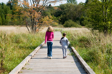 boy and girl walking on a boardwalk in fall