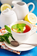 Tea with lemon, mint, and fresh cranberries on a blue background