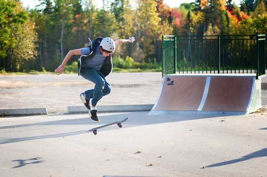 teen boy skateboarding at the local skate park on a beautiful fall evening