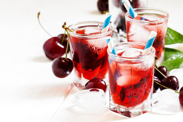 Cherry red drink with ice in a heart shape, selective focus