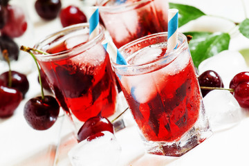 Cherry red drink with ice in a heart shape, selective focus