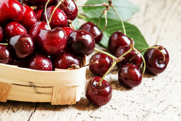 Dark red ripe cherries in a wicker basket, selective focus