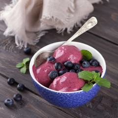 Blueberry ice cream with fresh blueberries and mint on a wooden table 