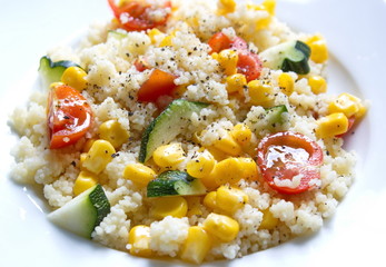 couscous served with corns, zucchini and tomatoes on tablecloth