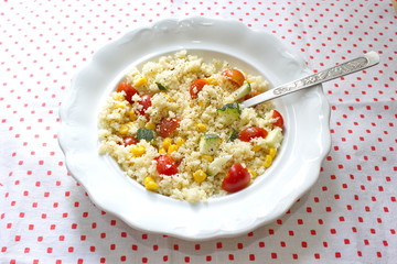 couscous served with corns, zucchini and tomatoes on tablecloth