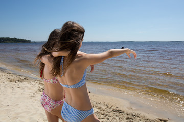 Back view of two sisters looking at the ocean