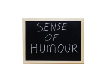 SENSE OF HUMOUR written with white chalk on blackboard.