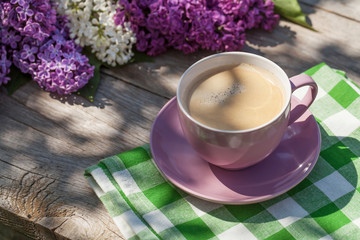 Obraz na płótnie Canvas Coffee cup and colorful lilac flowers