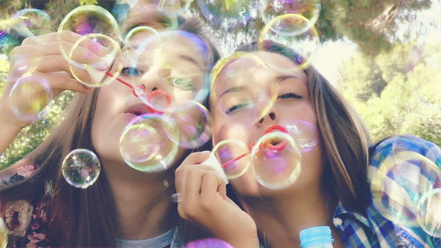 teenager playing happy in a park with soap bubbles closeup