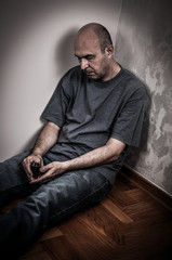 Obraz premium Drunk man sitting on the floor, sleeping and holding a glass of alcohol drink