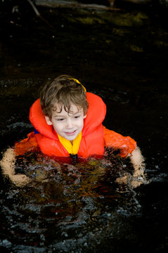 Little Boy In A Lake Wearing A Life Jacket