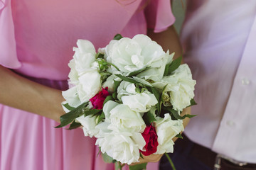 The bride is holding a wedding bouquet of beautiful flowers roses