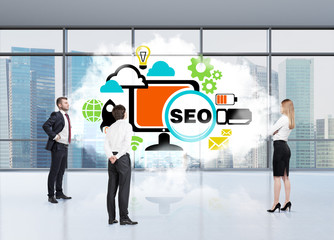 Three persons in an office are tackling with SEO. A cloud in an office space and a flowchart....